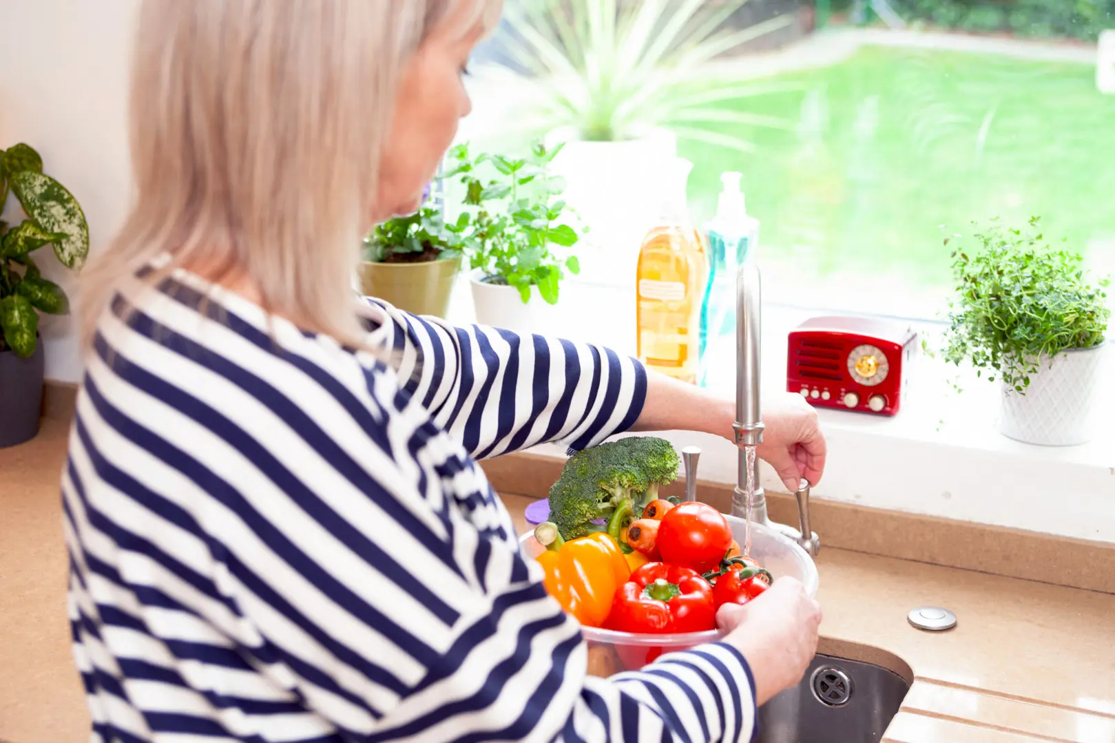 lady washing vegetables in a bowl