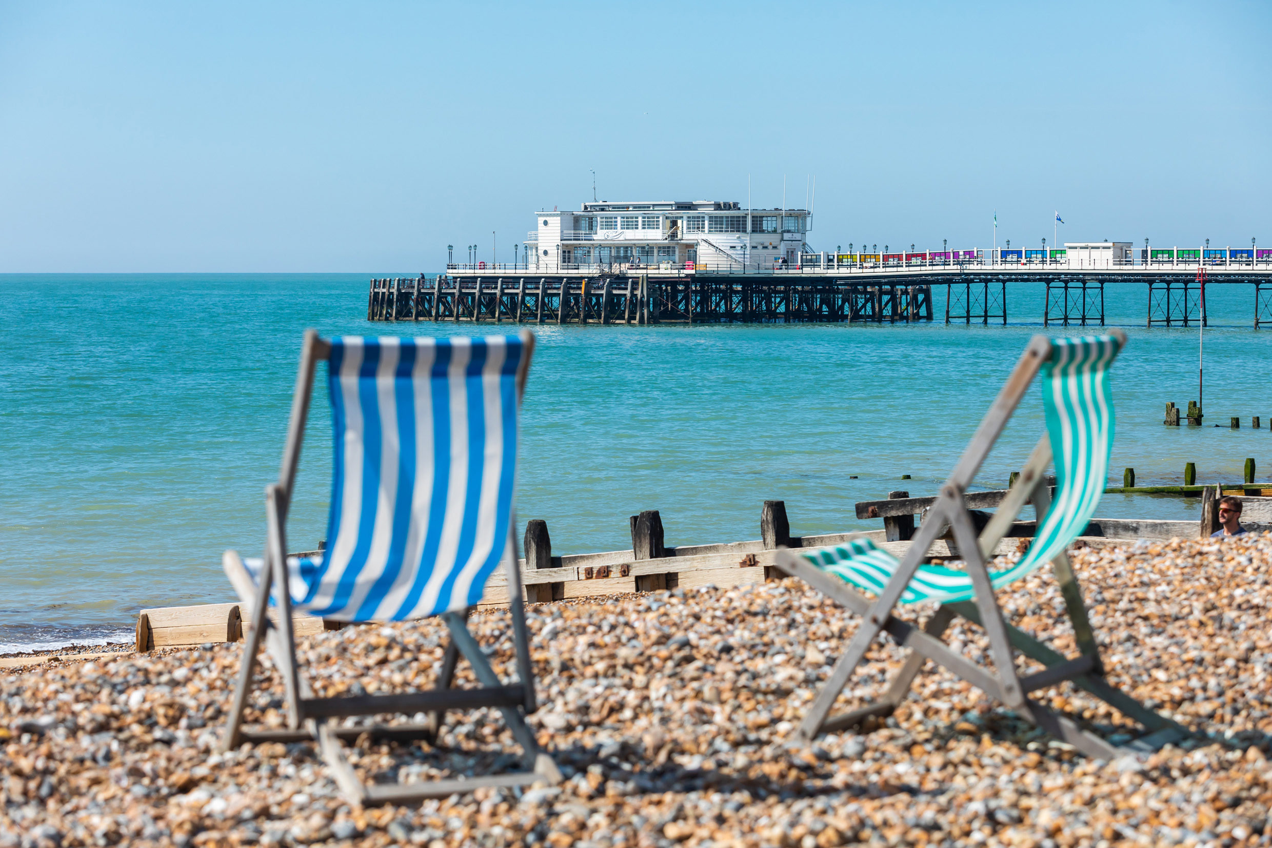 Two deckchairs on Worthing Beach with Worthing Pier in the background