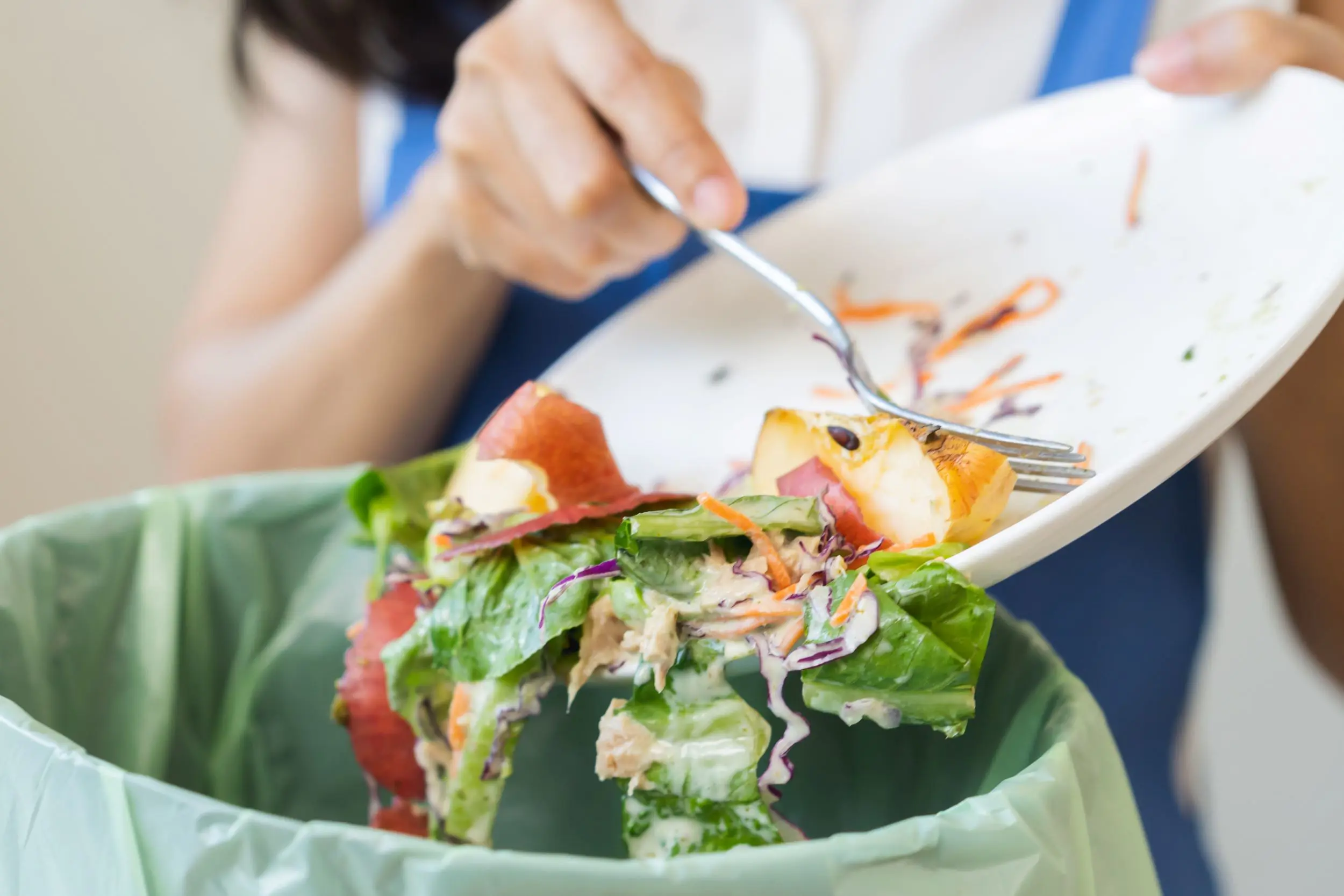 scraping leftover food into a bin