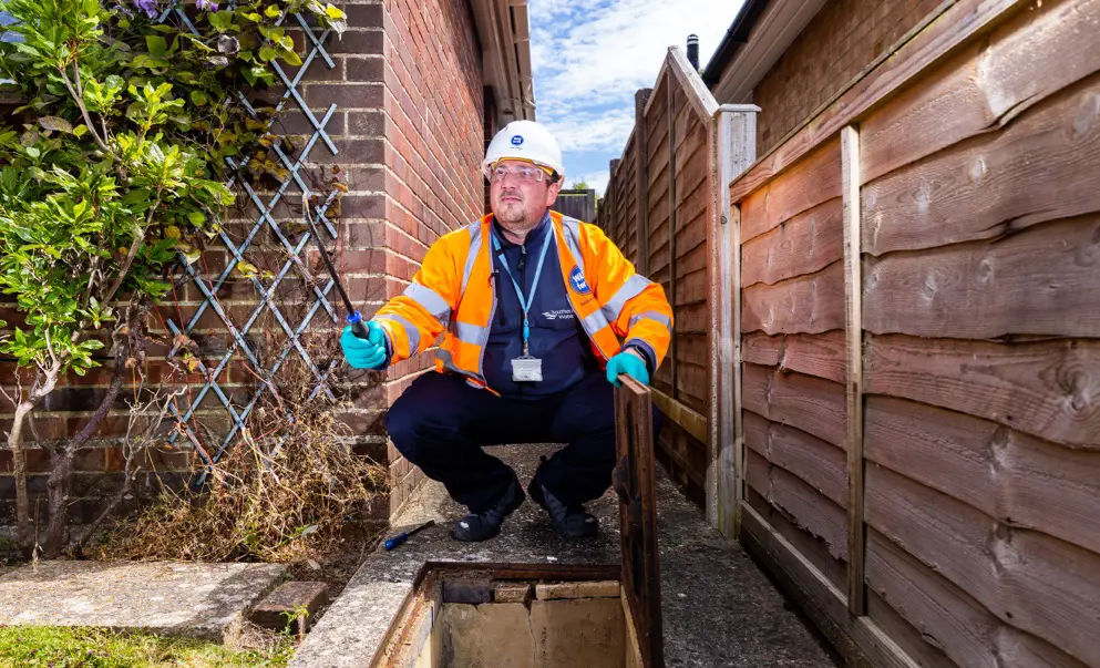 Worker crouching above sewer