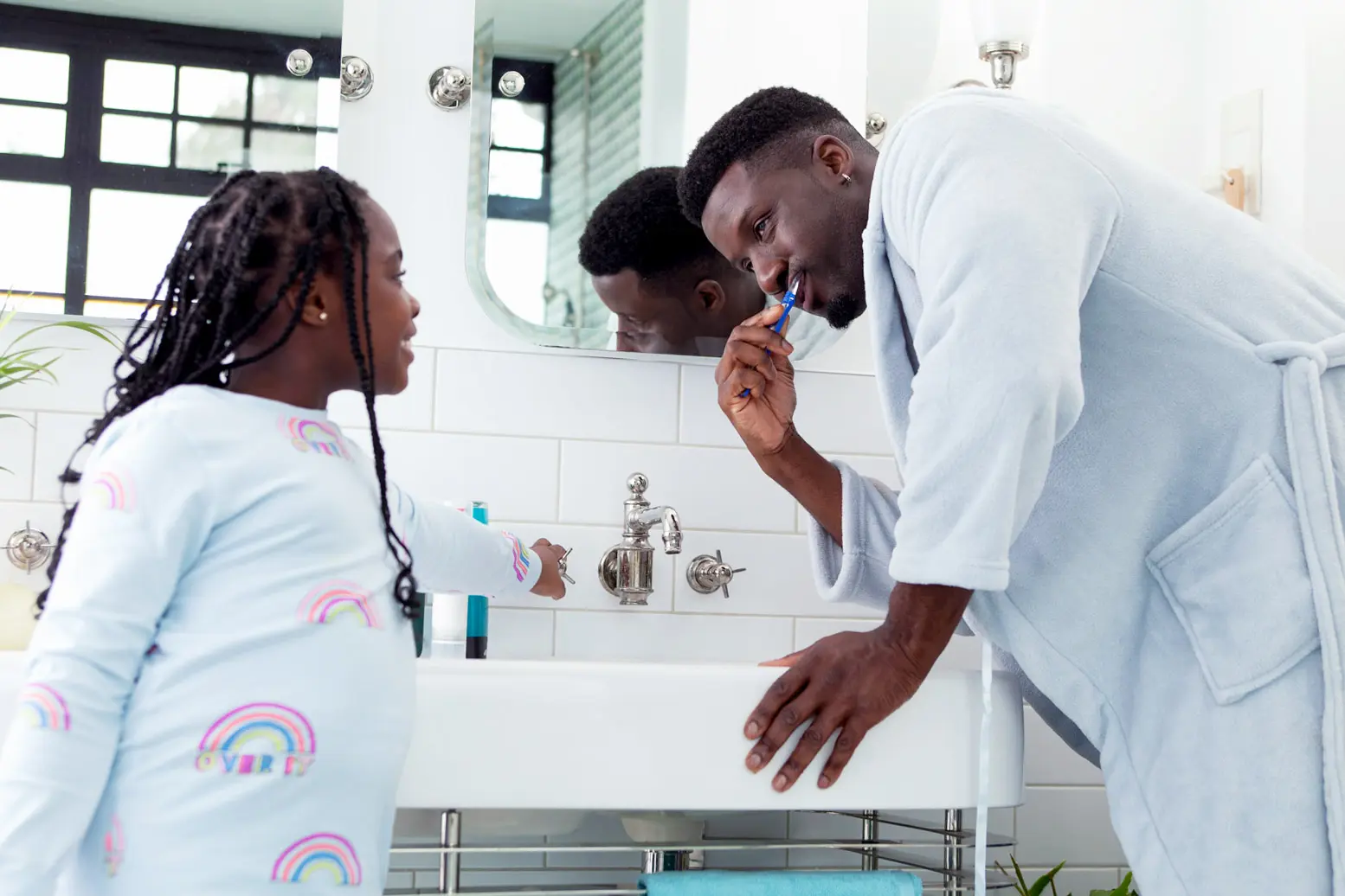 father and daughter brushing teeth in a bathroom