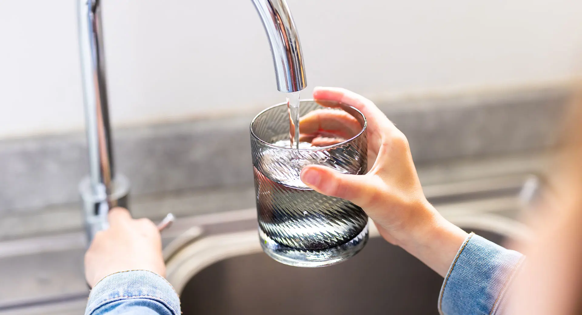 A close-up of a person filling a glass of water from a tap