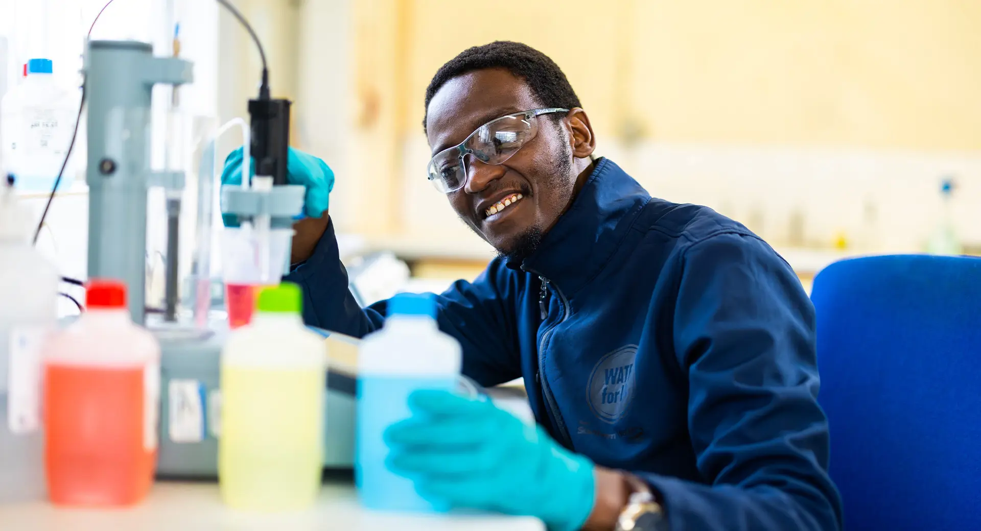 A person wearing safety goggles examinig water and running tests